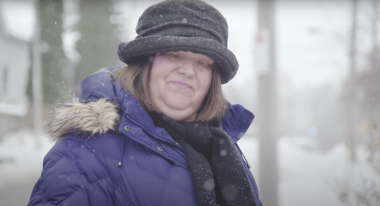 Woman with a disability wearing a hat while standing in the snow.