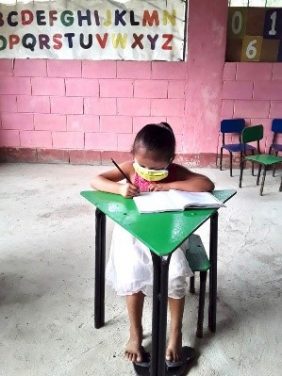 A girl in guatemala studying at a school desk