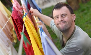 Smiling man with a disability hanging clothes on a clothesline.