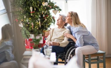 Young woman holding an older lady in a wheel chair at christmas