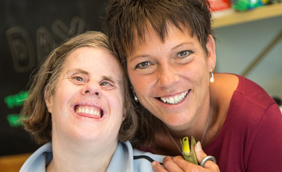 A woman hugging another woman with a disability.