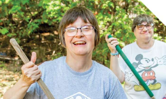 Women smiling and holding rakes
