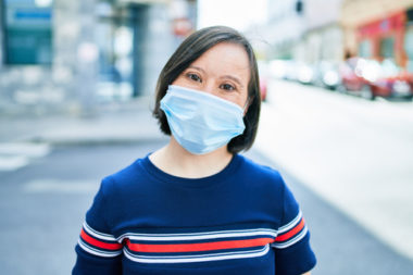 A woman with a disability wearing a blue non medical mask.