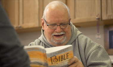 Man with a disability reading a bible.