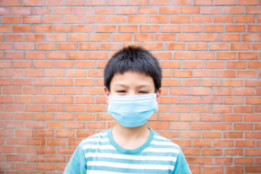 Young boy wearing a blue non medical mask.