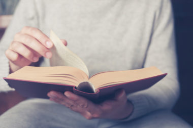 Close-up image of a person flipping the page of a book.