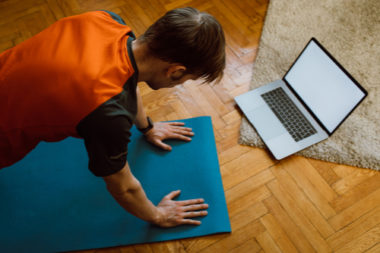 A man at his home participating in an online yoga class.