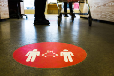 A red circle on the floor of a grocery store indicating that people must maintain two metres of distance between one another.
