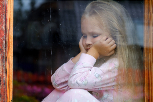 Young girl sulking beside window.