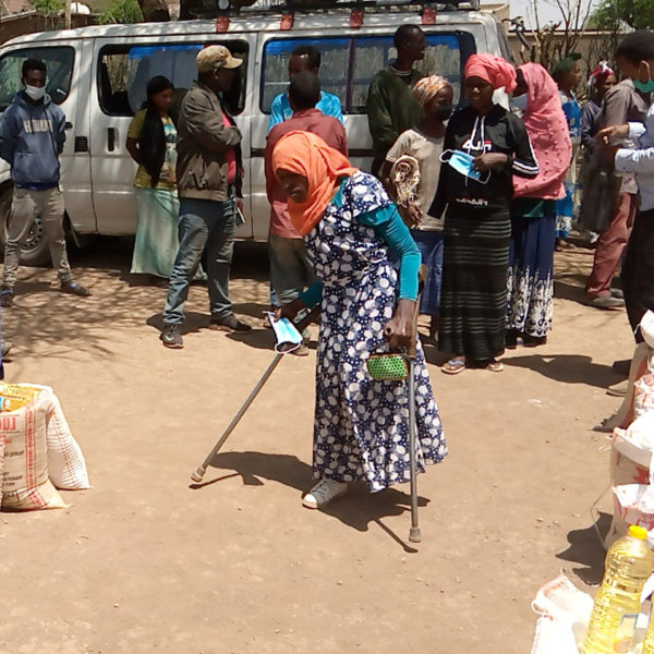Woman using crutches in village.